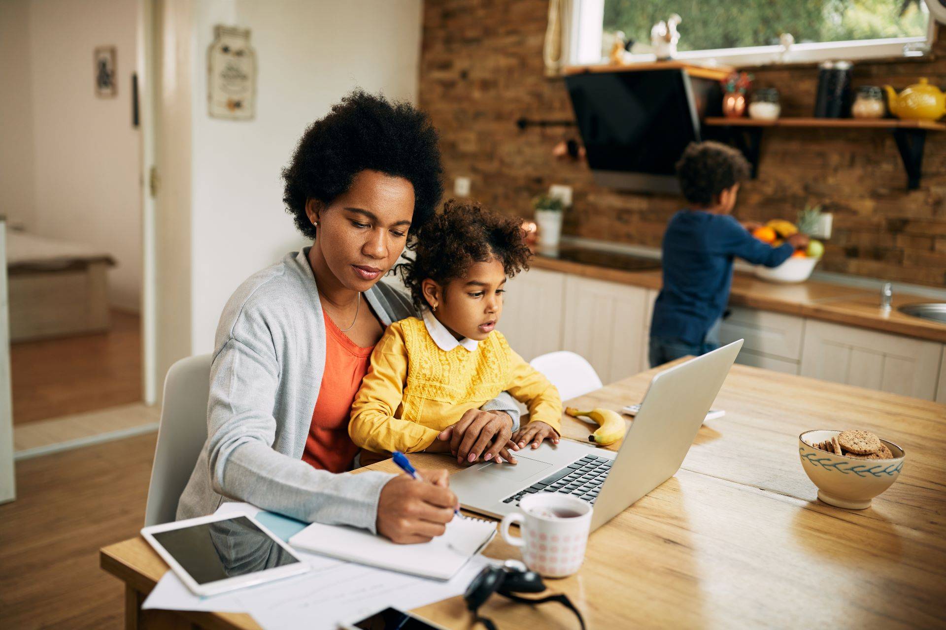 Alleinerziehende Mutter mit Kind bei der Jobsuche am Laptop